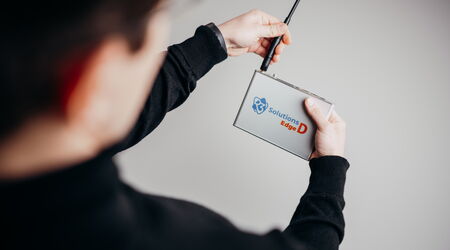 A person demonstrates the advanced functionality of the Edge D device, holding it with an antenna.