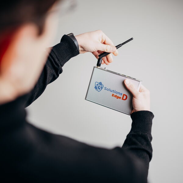 A person interacts creatively with the Solutions Edge D device using a pen in a minimalistic setting. (Text KI-generiert)